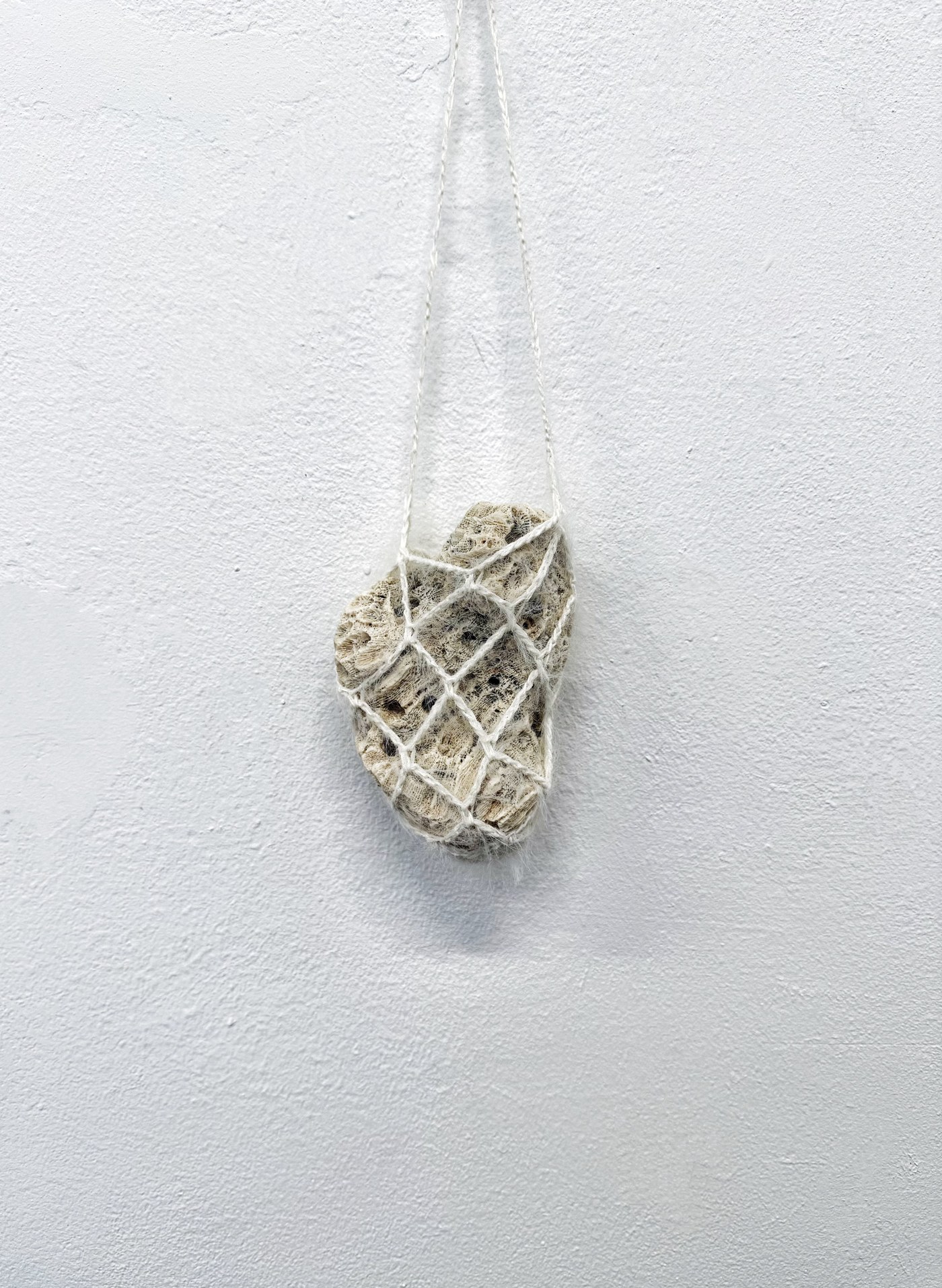 Holding, 2025 — Yuchen Liu. Heart-shaped coral stones, crocheted cotton thread.